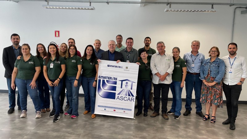 Secretário Covatti e grupo com cerca de 20 pessoas, postam com banner da Emater