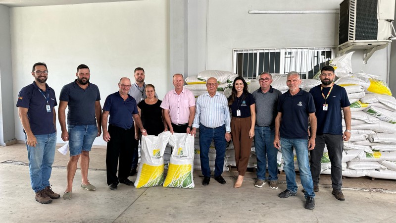 Onze pessoas posam para foto à frente de sacos de sementes do Programa de Sementes e Mudas Forrageiras