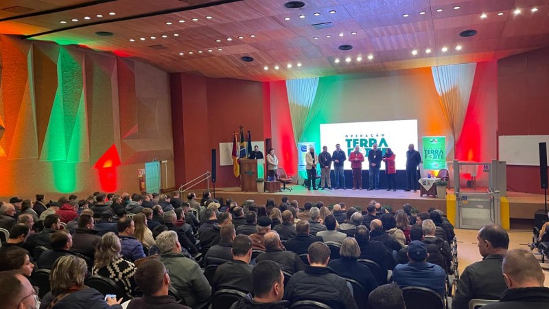 Imagem mostra imagem ampla do público e das autoridades no palco