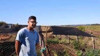 Imagem mostra o jovem Alan da Silva Mohr em frente ao seu canteiro de Hortali&ccedil;as